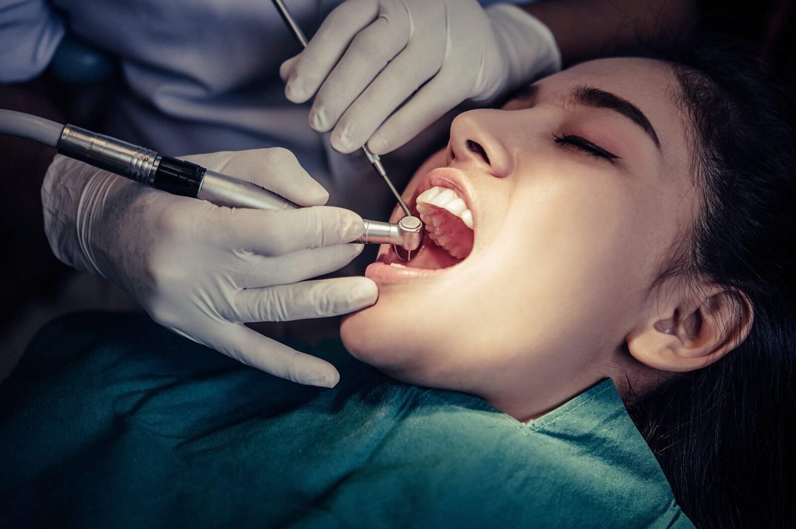 Woman receiving dental cosmetic treatment with dental tools in a clinic setting.